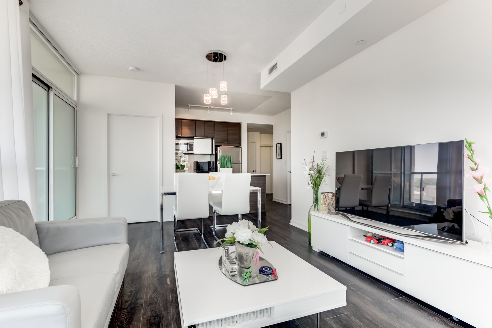 Open-concept living and dining room with dark floors and white walls at 62 Forest Manor Rd Unit 1803, Toronto.