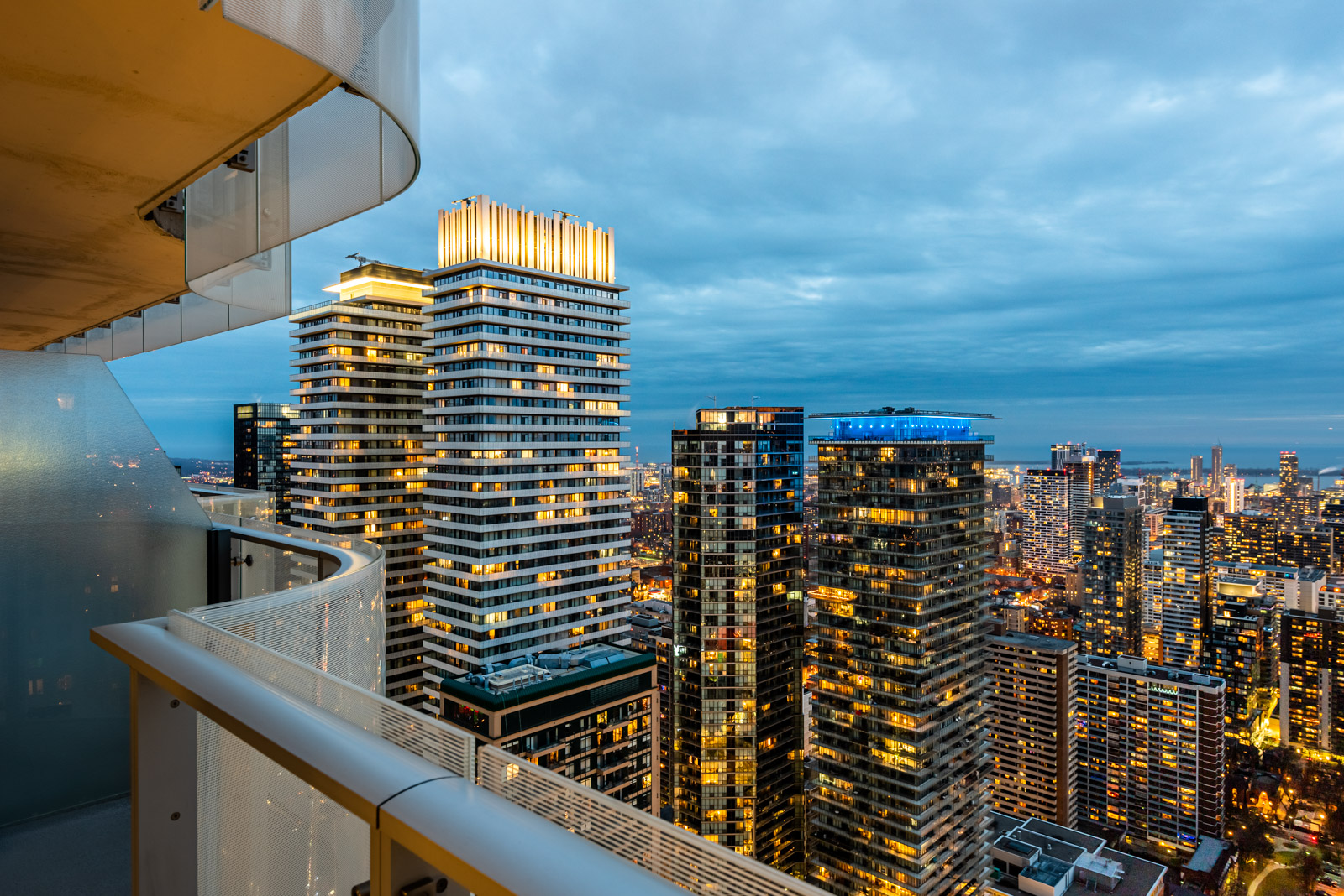 Toronto skyline at night with glittering gold lights, red-purple CN Tower, and cars along Yonge and Bloor.