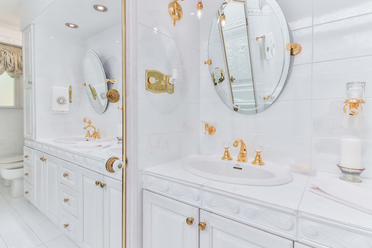 Gorgeous bathroom with his and her sinks, oval mirrors and white cabinets.