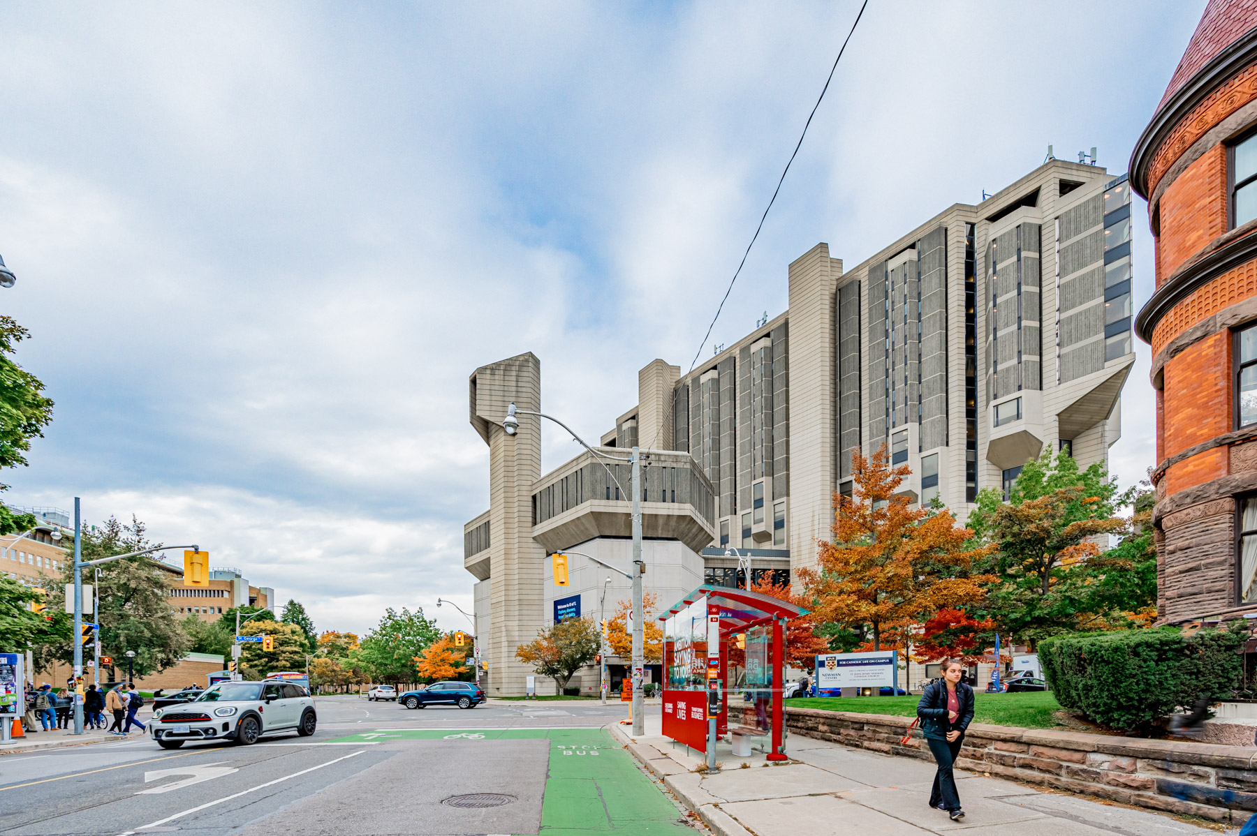 Cars and pedestrians foreground; University of Toronto Library in background.