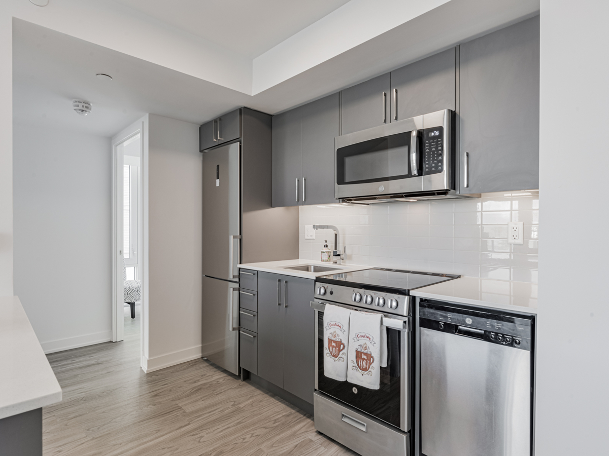 Condo kitchen with white marble counters, dark cabinets and white tile back-splash.