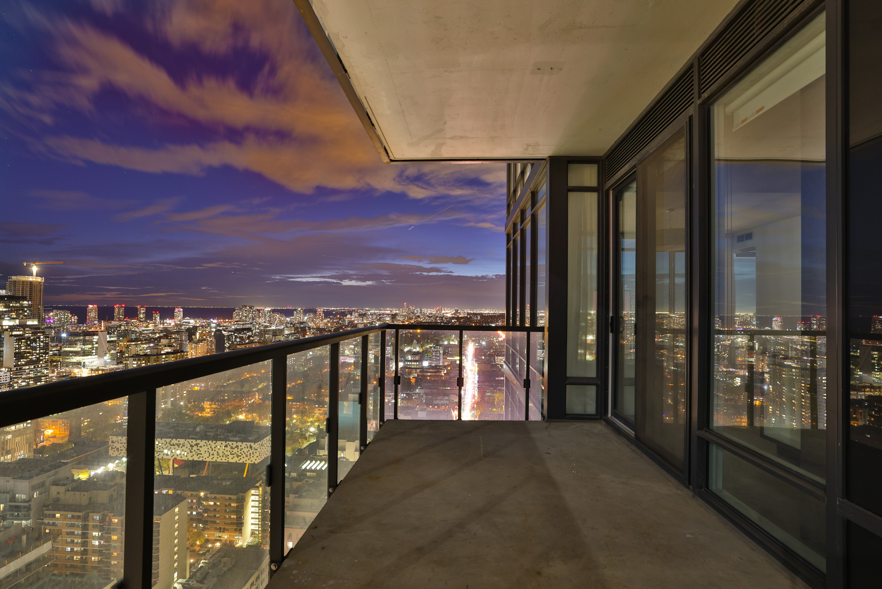 Condo balcony with view of Toronto skyline at night.