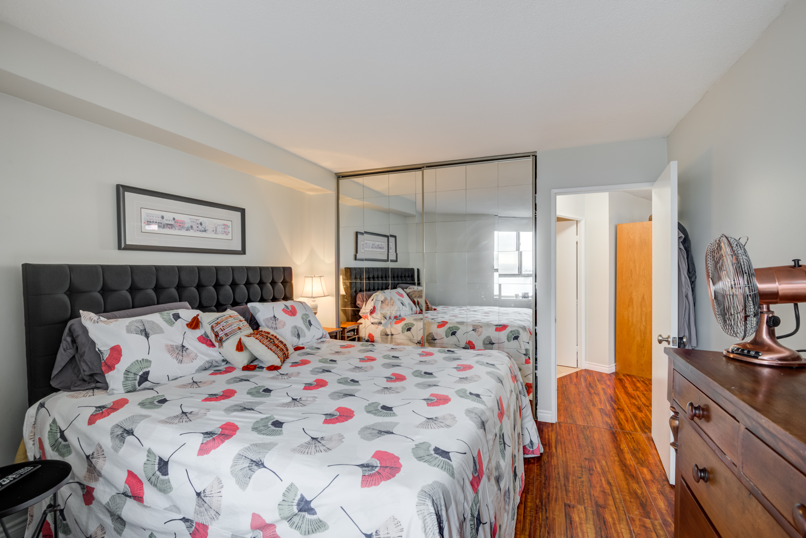 King-sized bed and closet with sliding mirror doors reflecting light.