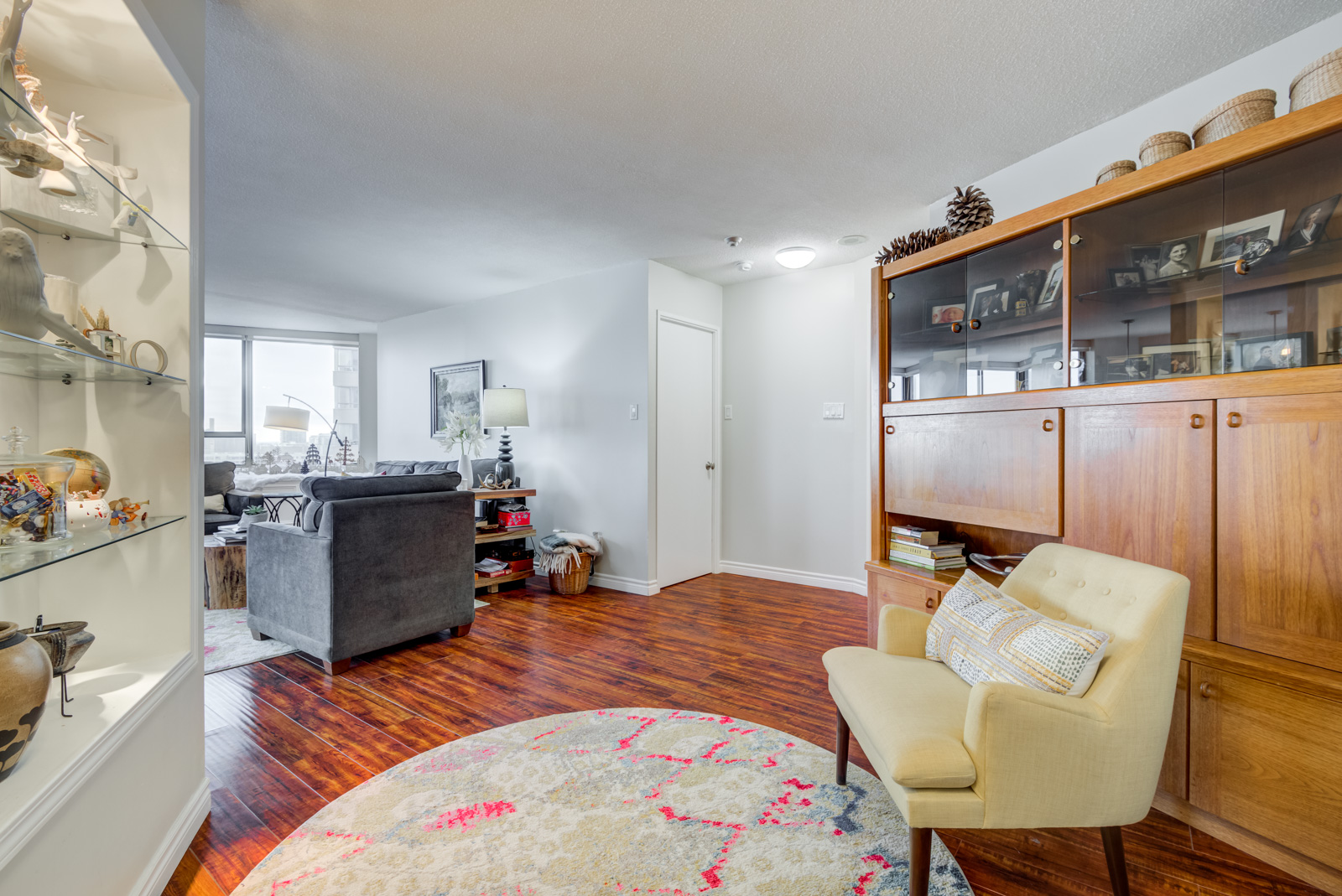 Den with arm chair, circular carpet and shelves with knick-knacks.