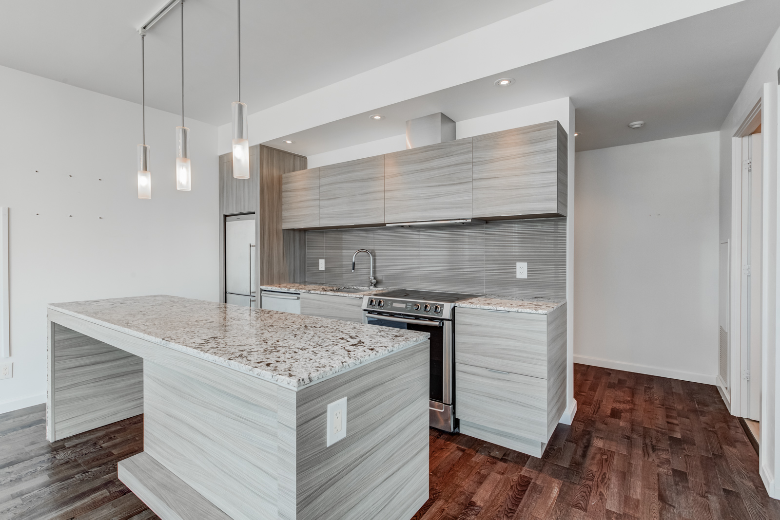 Kitchen island with speckled marble countertop and lighter base with wooden finish.