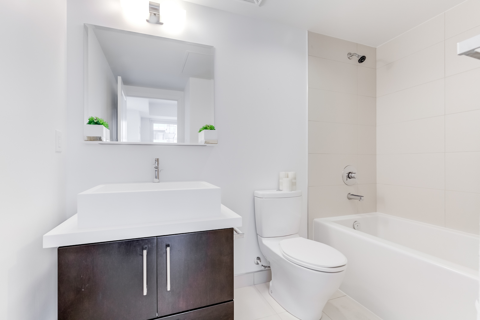 Master bath with white and gray colours and brown vanity.