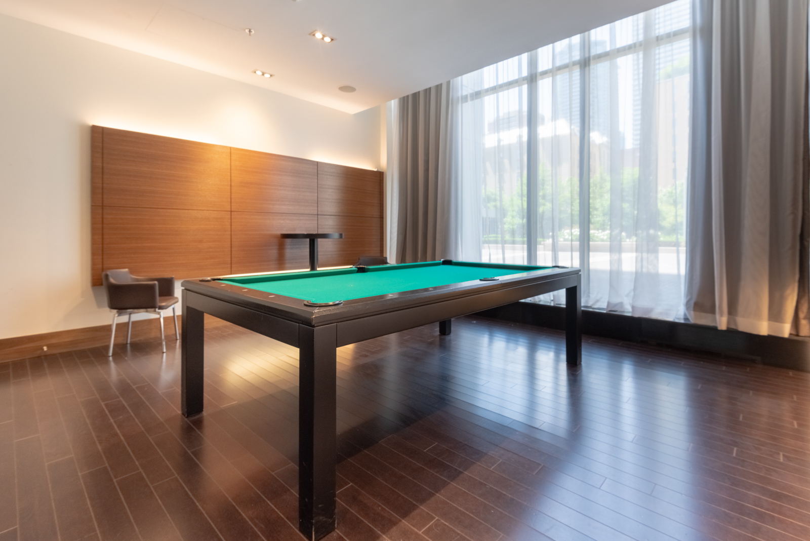 Empty room with large billiards table with green surface and dark brown floors at The Couture.