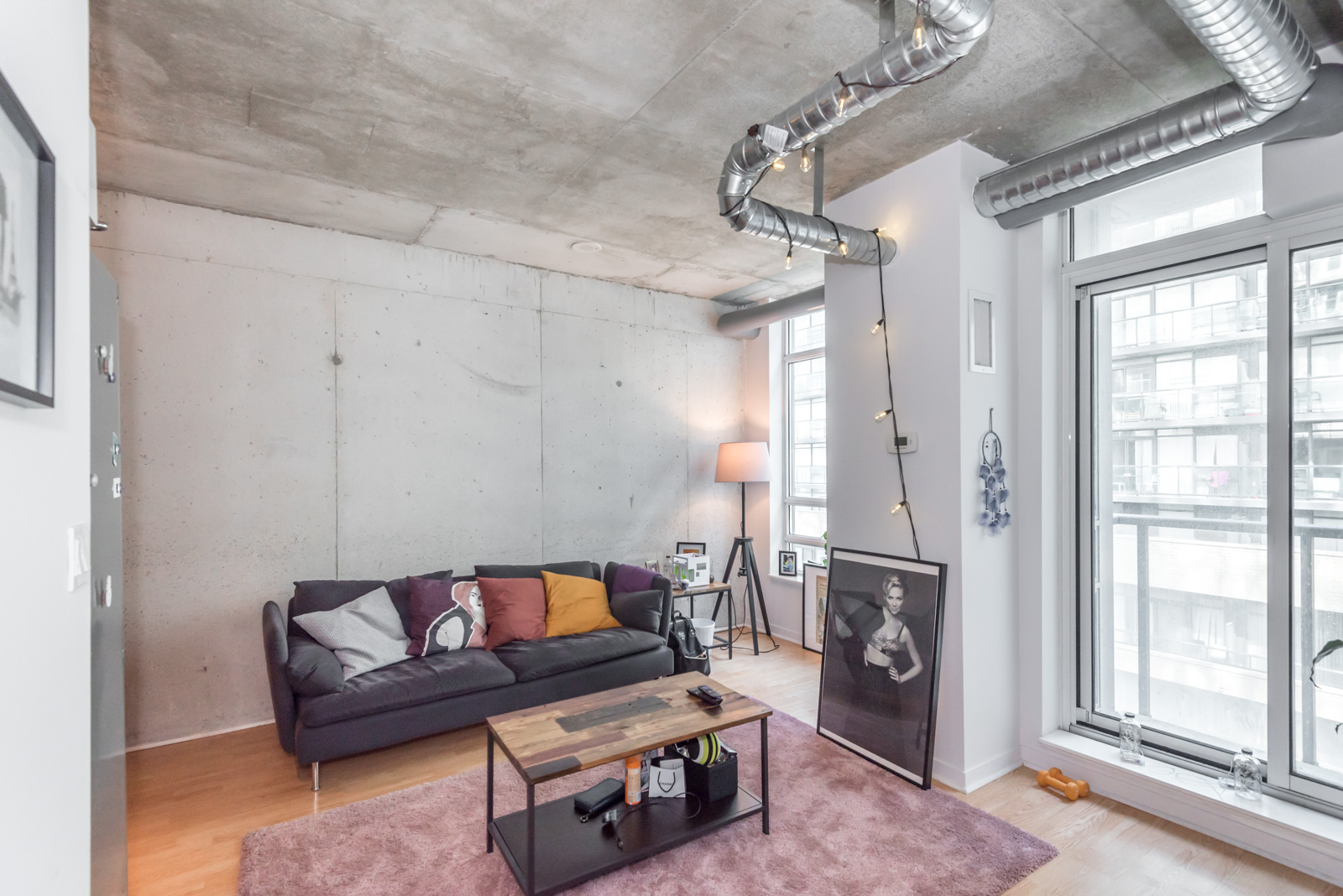 Image of living room from another angle. We see a sofa and table and rather huge ceiling.