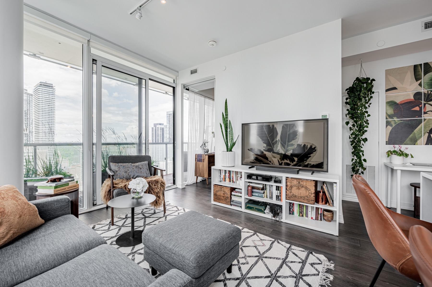 Condo living room with potted plants and dark laminate floors.