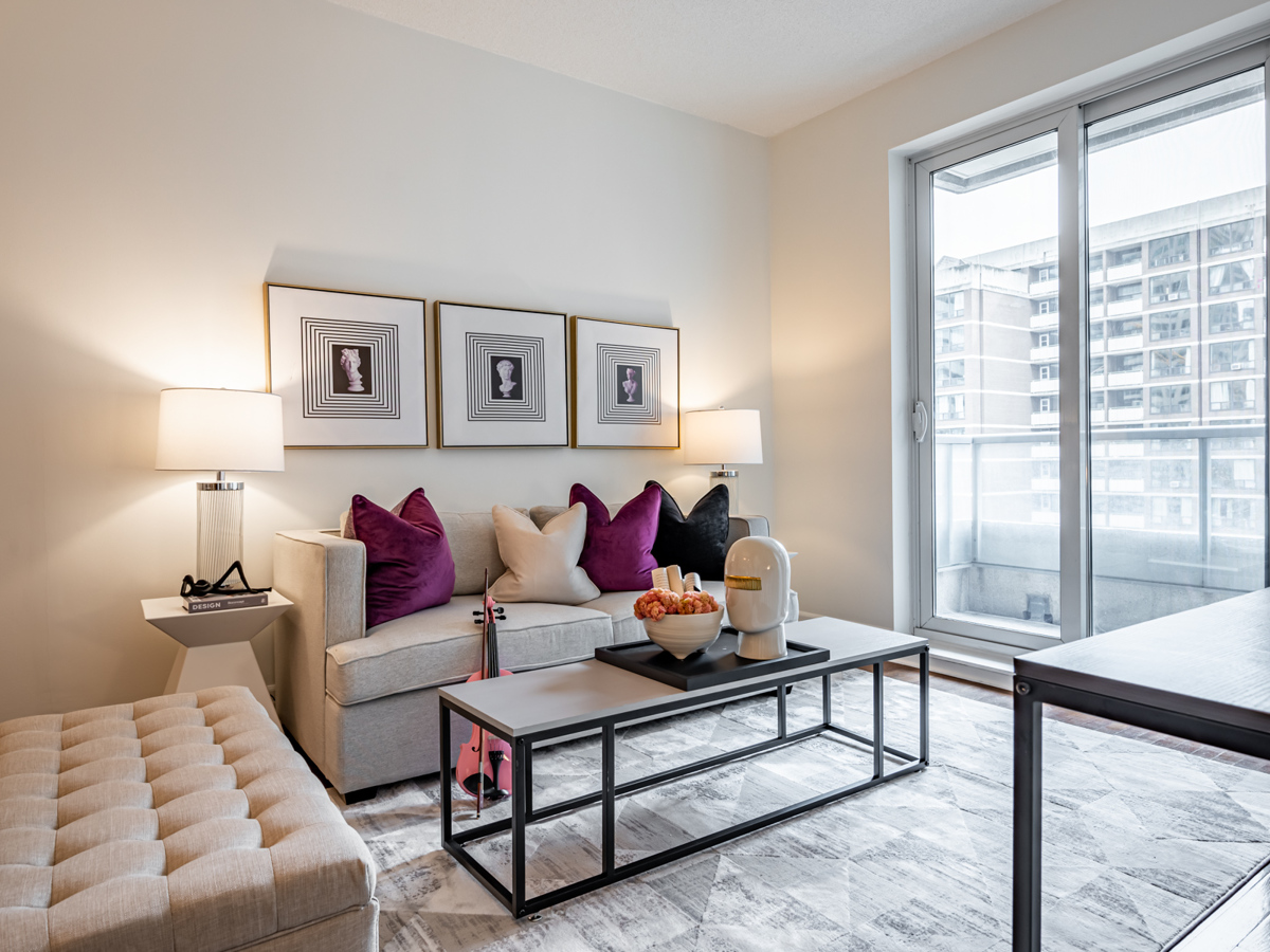 Condo living room with gray walls, gray sofa and purple pillows.