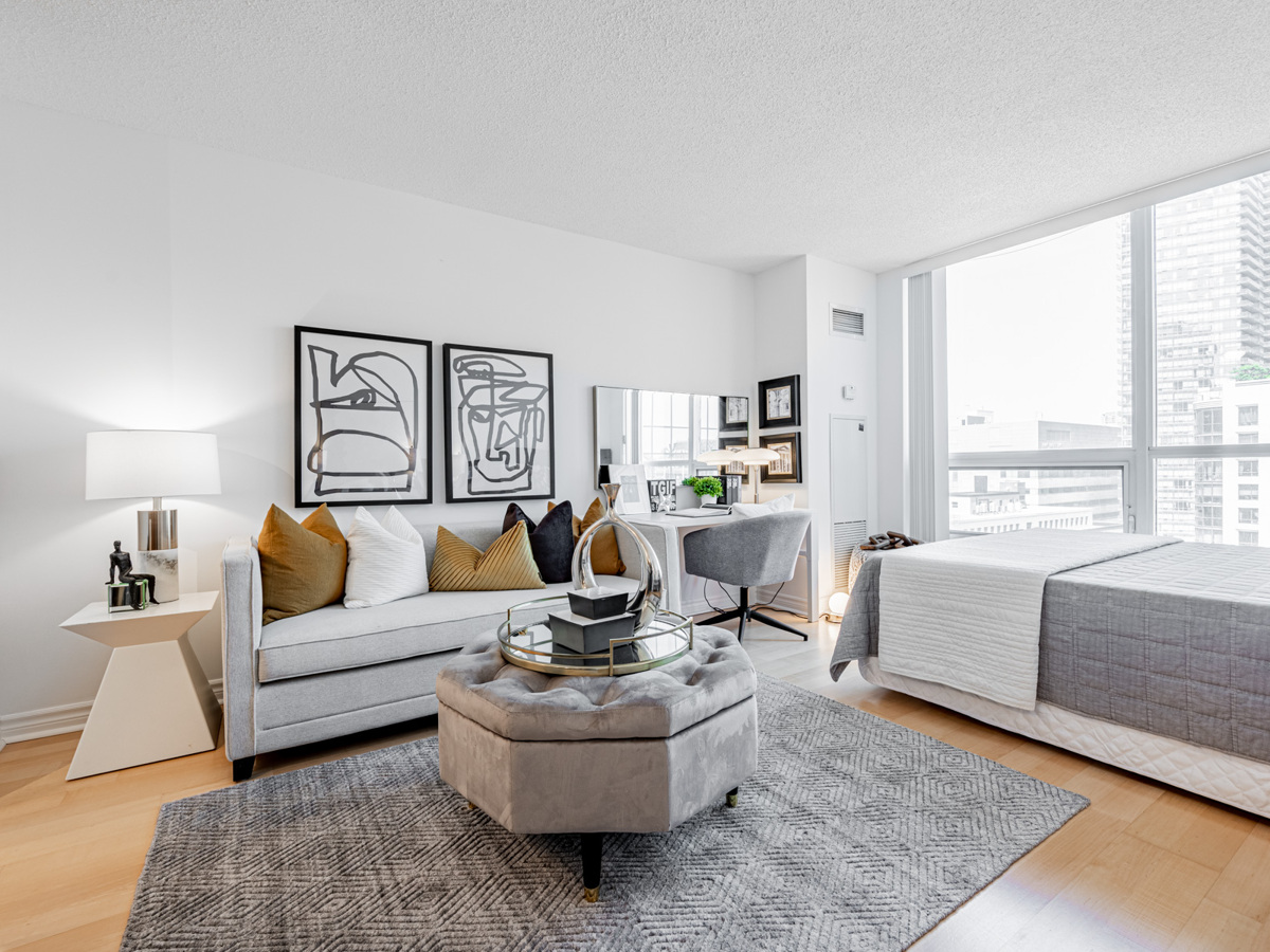 Bachelor's condo living room with couch, ottoman, table, desk and bed.