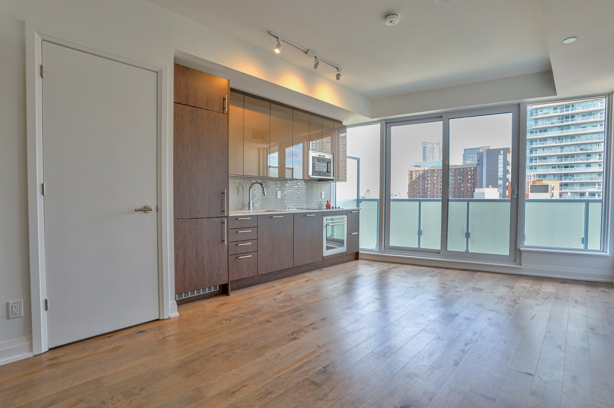 Empty condo with hardwood floors and large windows.