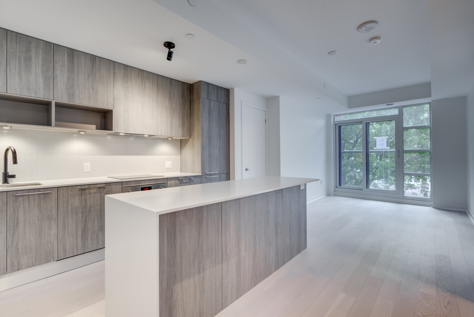 501 Adelaide St W Unit 408 – empty kitchen, dining and living room with light laminate floors and walls.