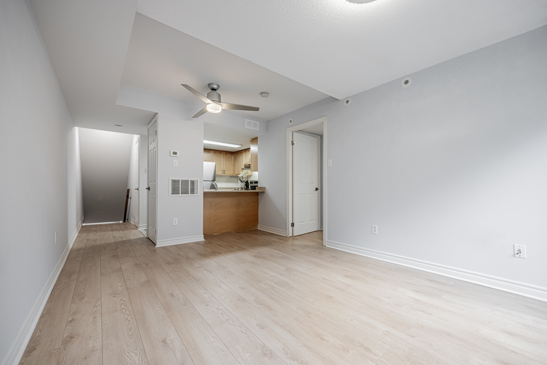 Townhouse living room with light-coloured 6-inch wide plank laminate floors.