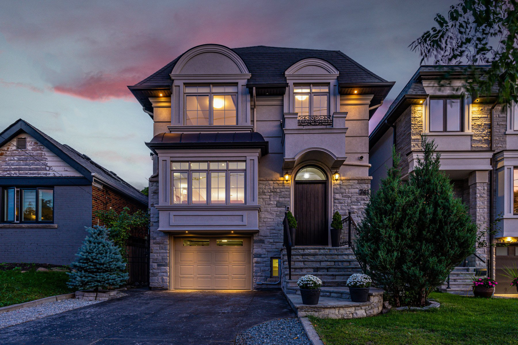 Golden glow of pot lights on facade of 741 Glencairn Ave during evening.