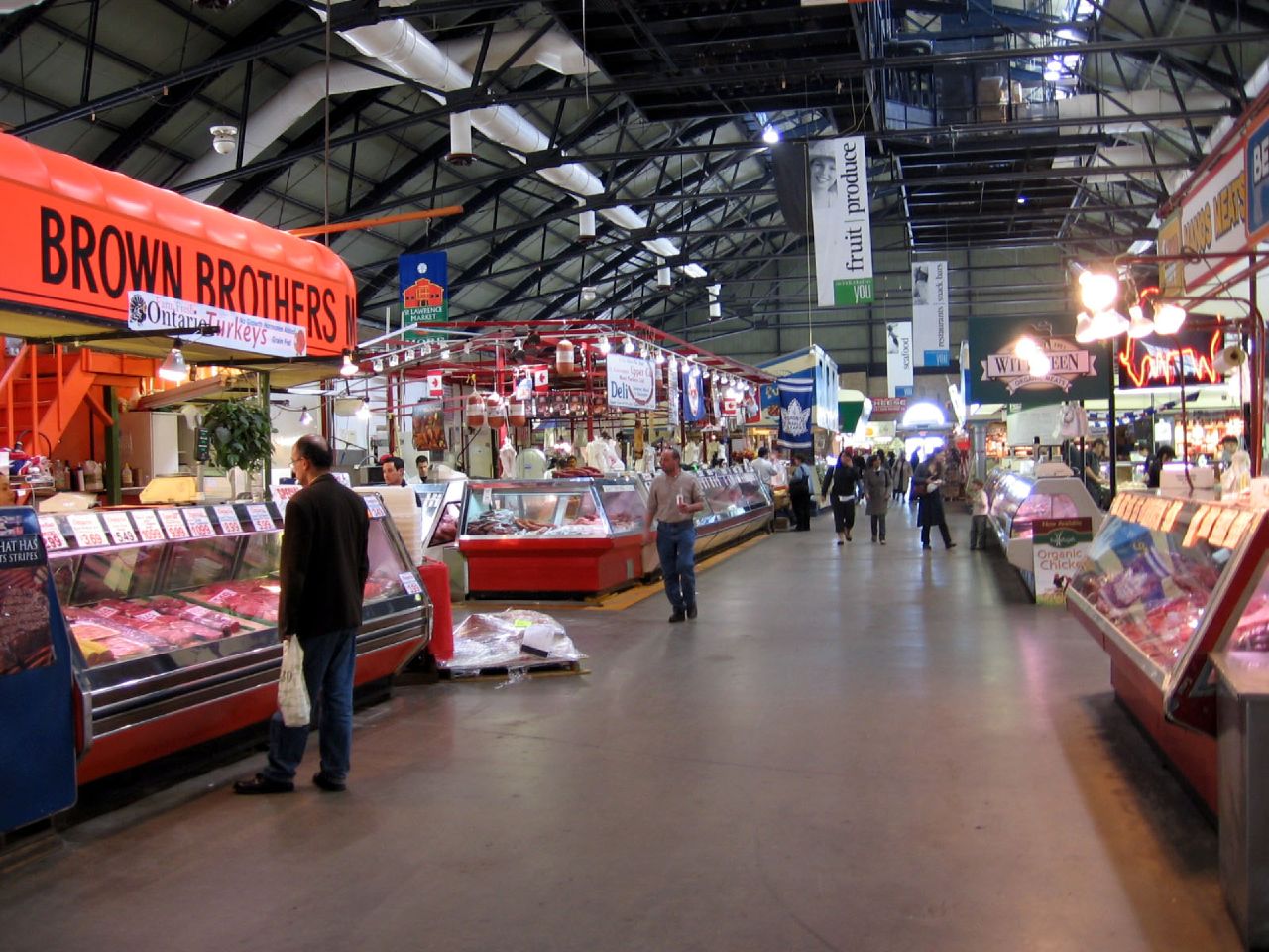 Stalls and people shopping at market.