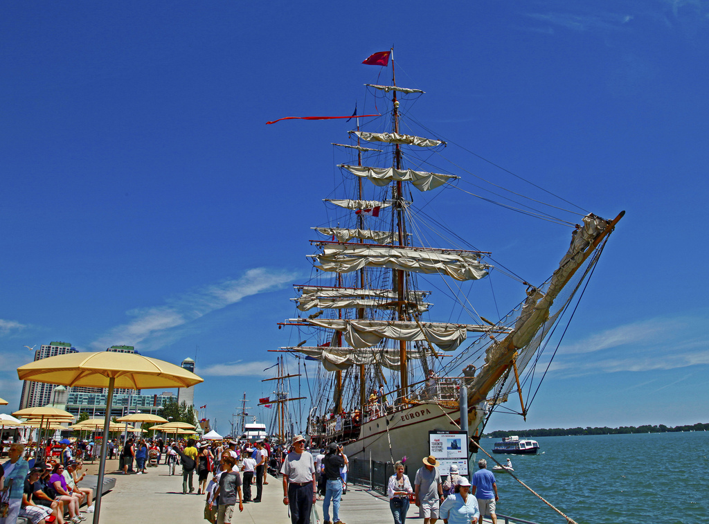 Tall-ship in Toronto Harbour and people walking along boardwalk.