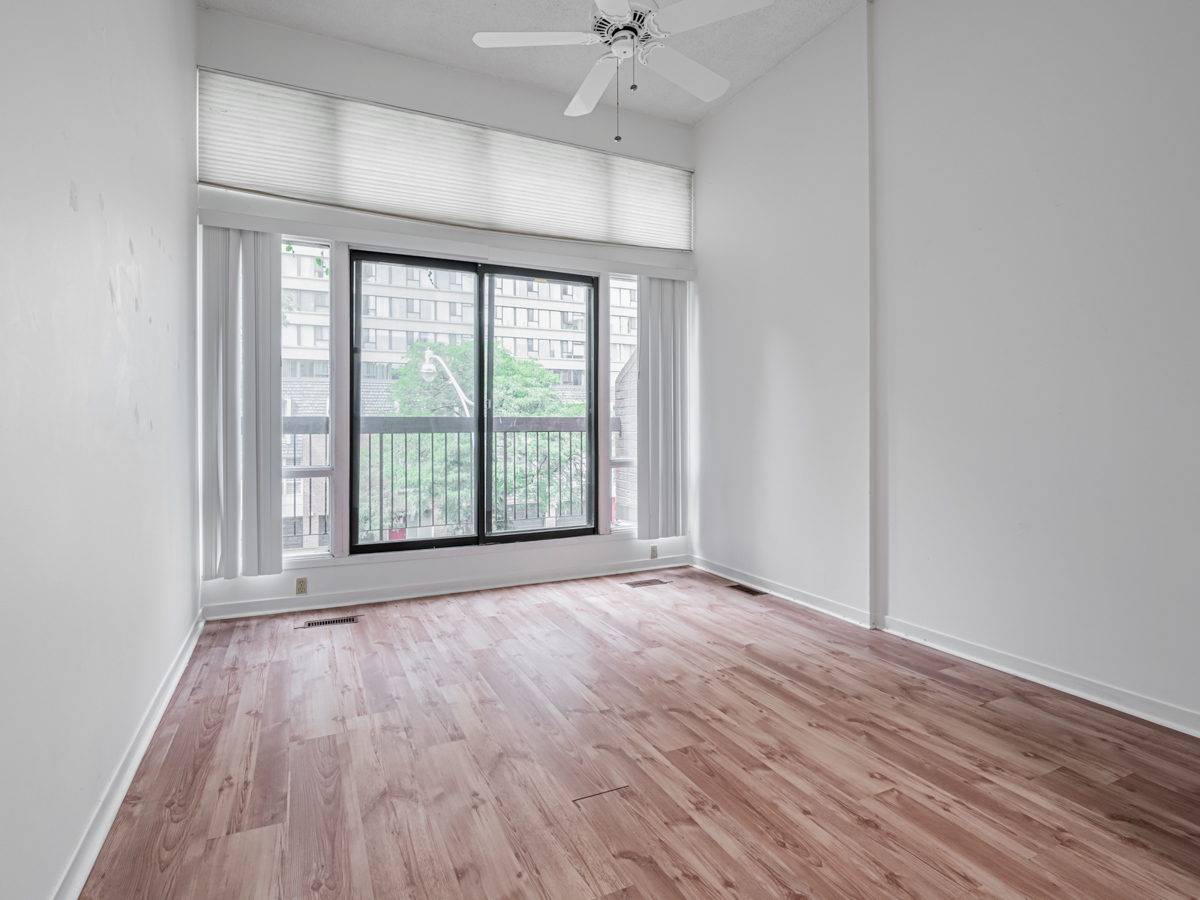 Bedroom with light brown laminate floors and Hunter Douglas blinds.