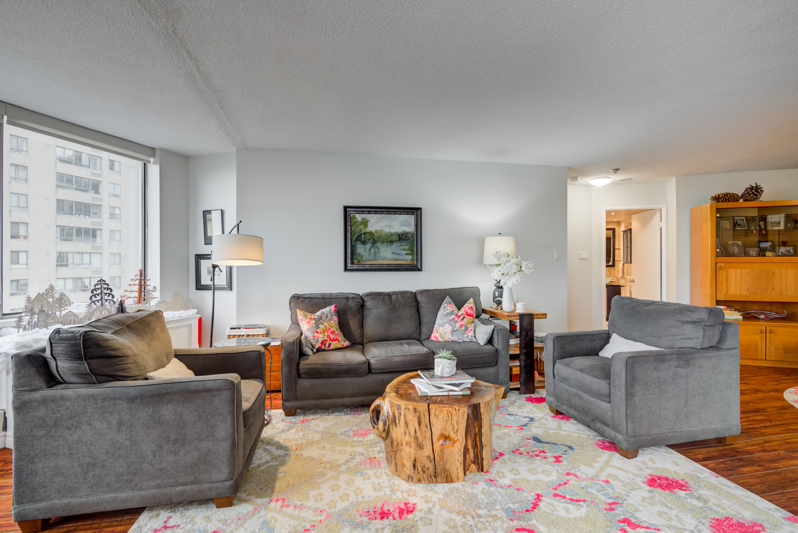 Living room with dark gray sofas and tree stump for coffee table.