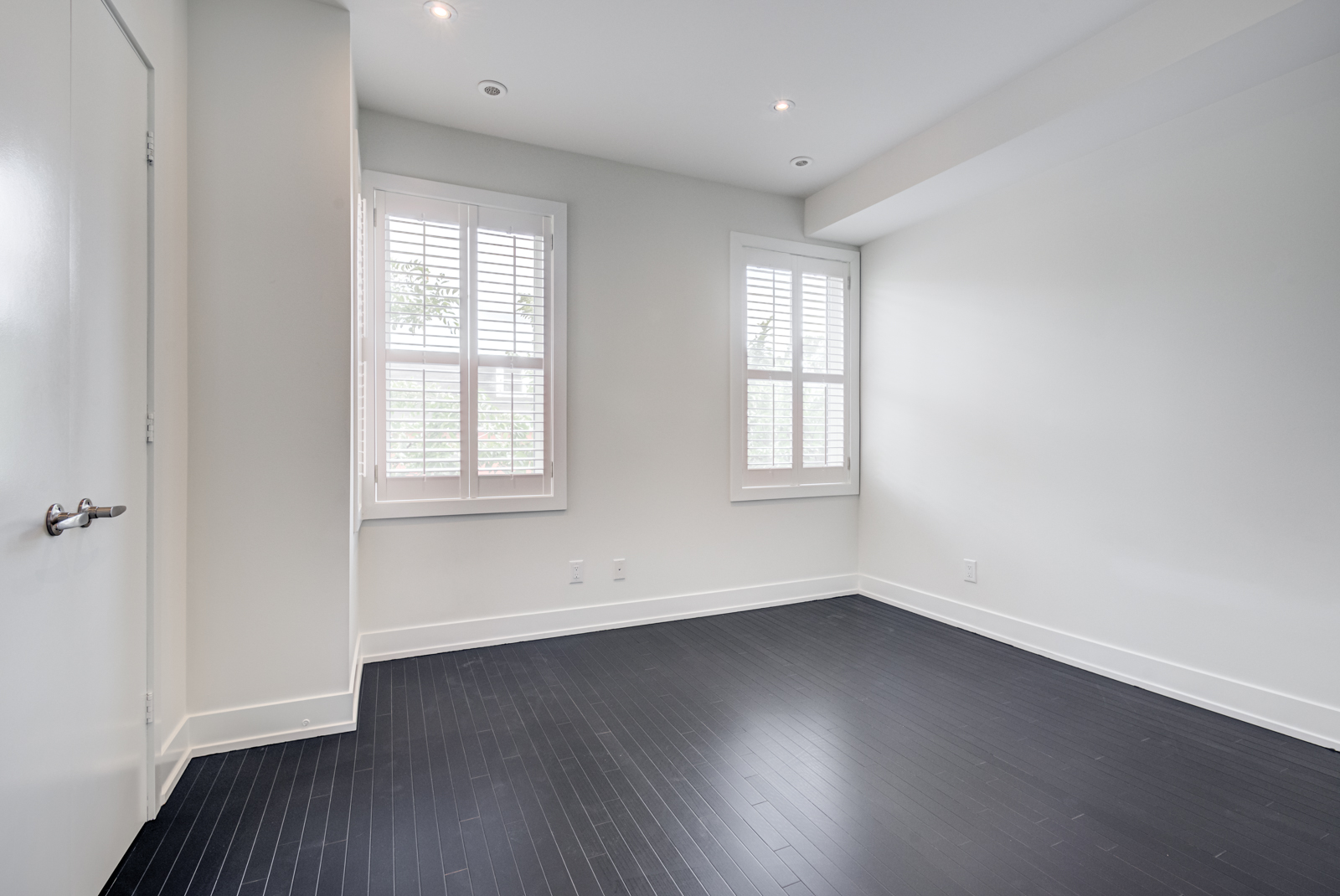 empty bedroom with black hardwood floors and gray walls