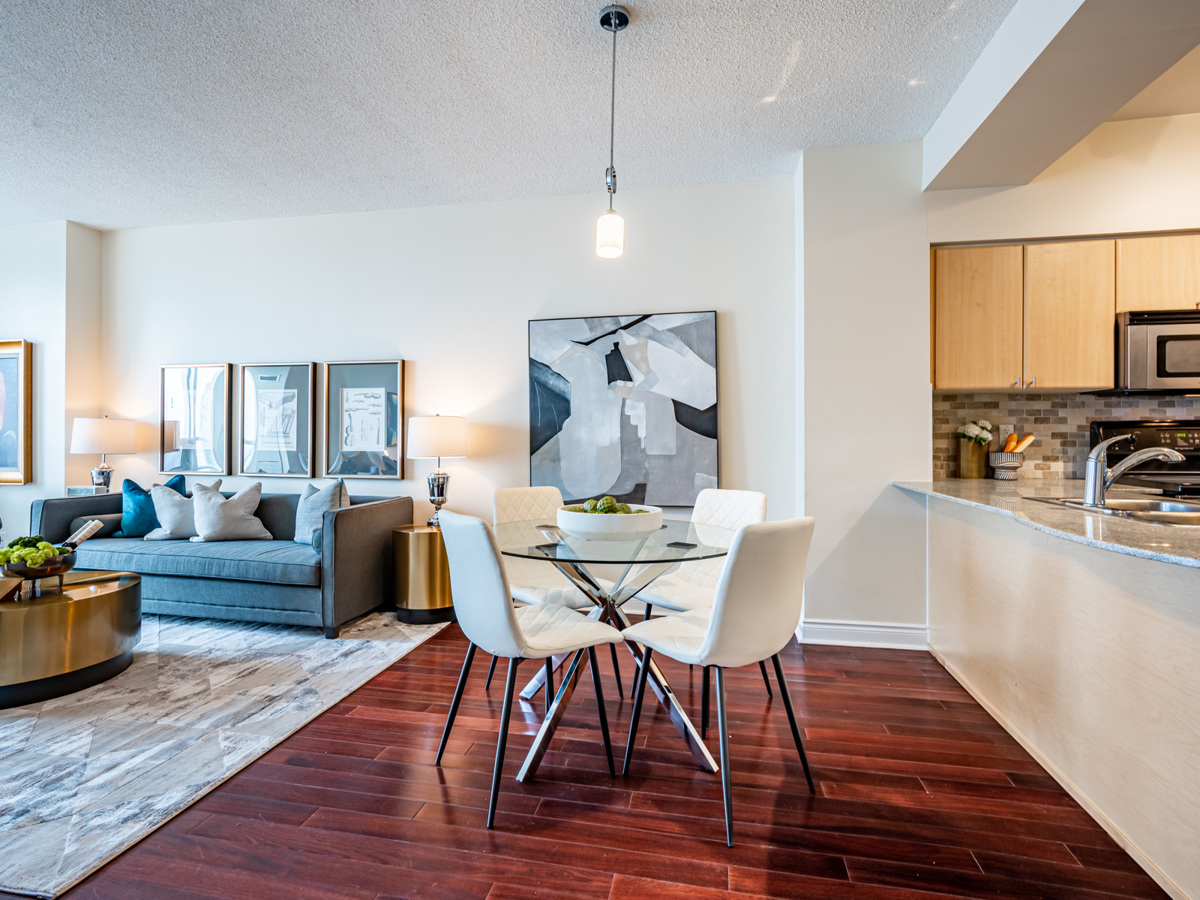 Condo with dark hardwood floors, brown door and light-coloured walls.