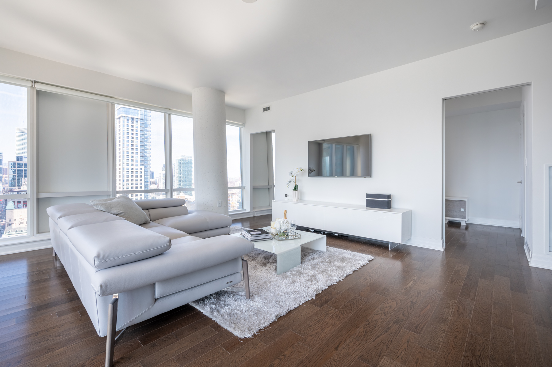 8 The Esplanade Ave Suite 3305 living room with gray sectional, table, TV stand and rug.