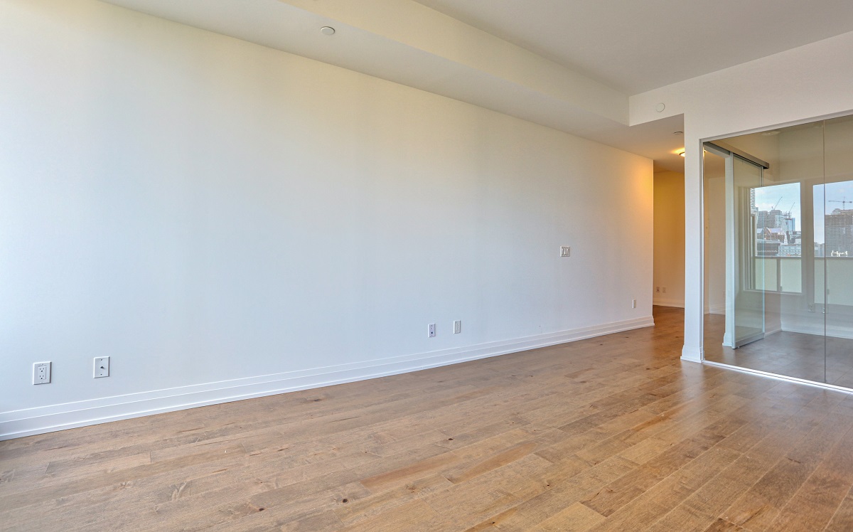 Brightly lit empty condo with hardwood floors.