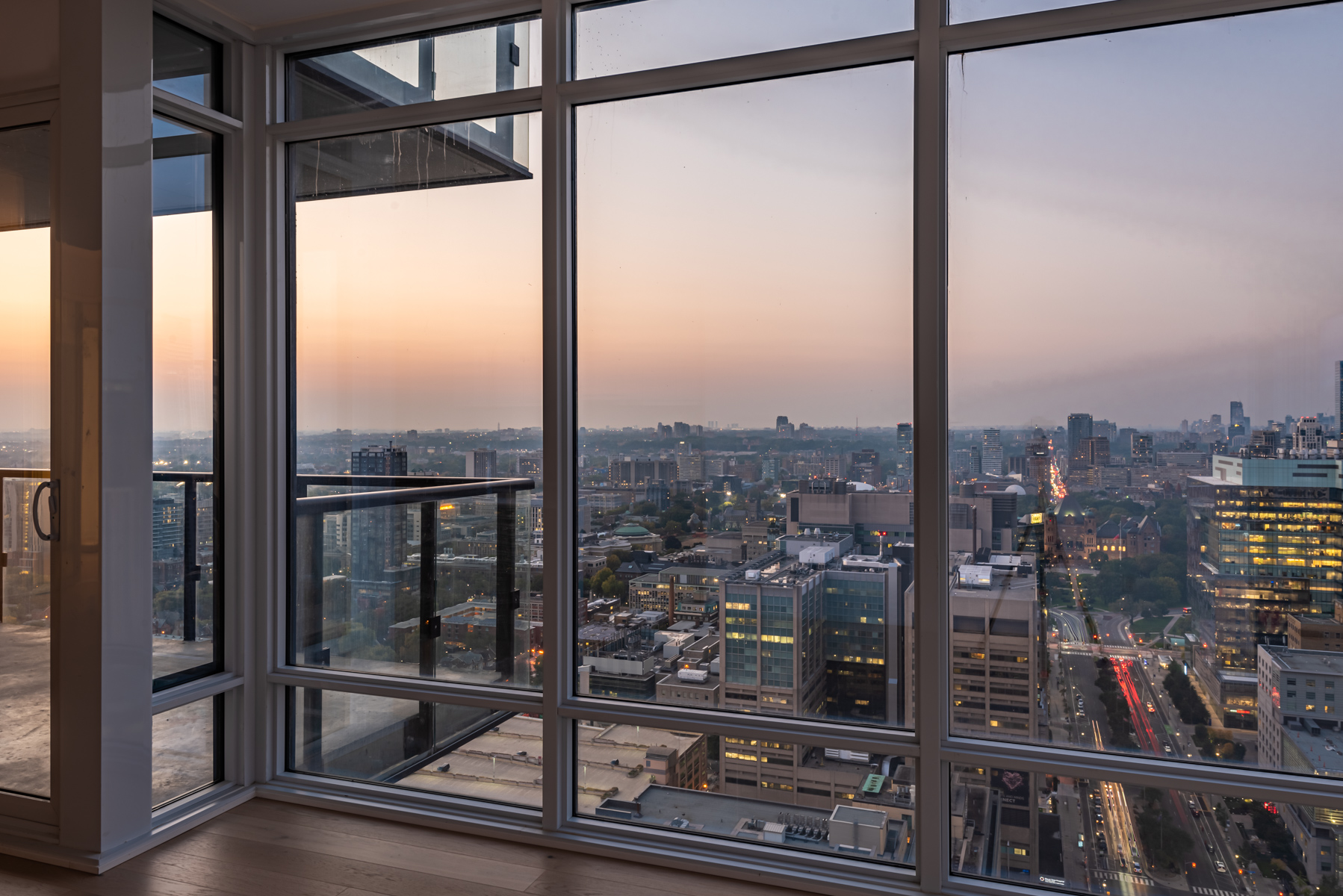 View of Toronto from living room of 488 University Ave showing pinkish sky and city lights.