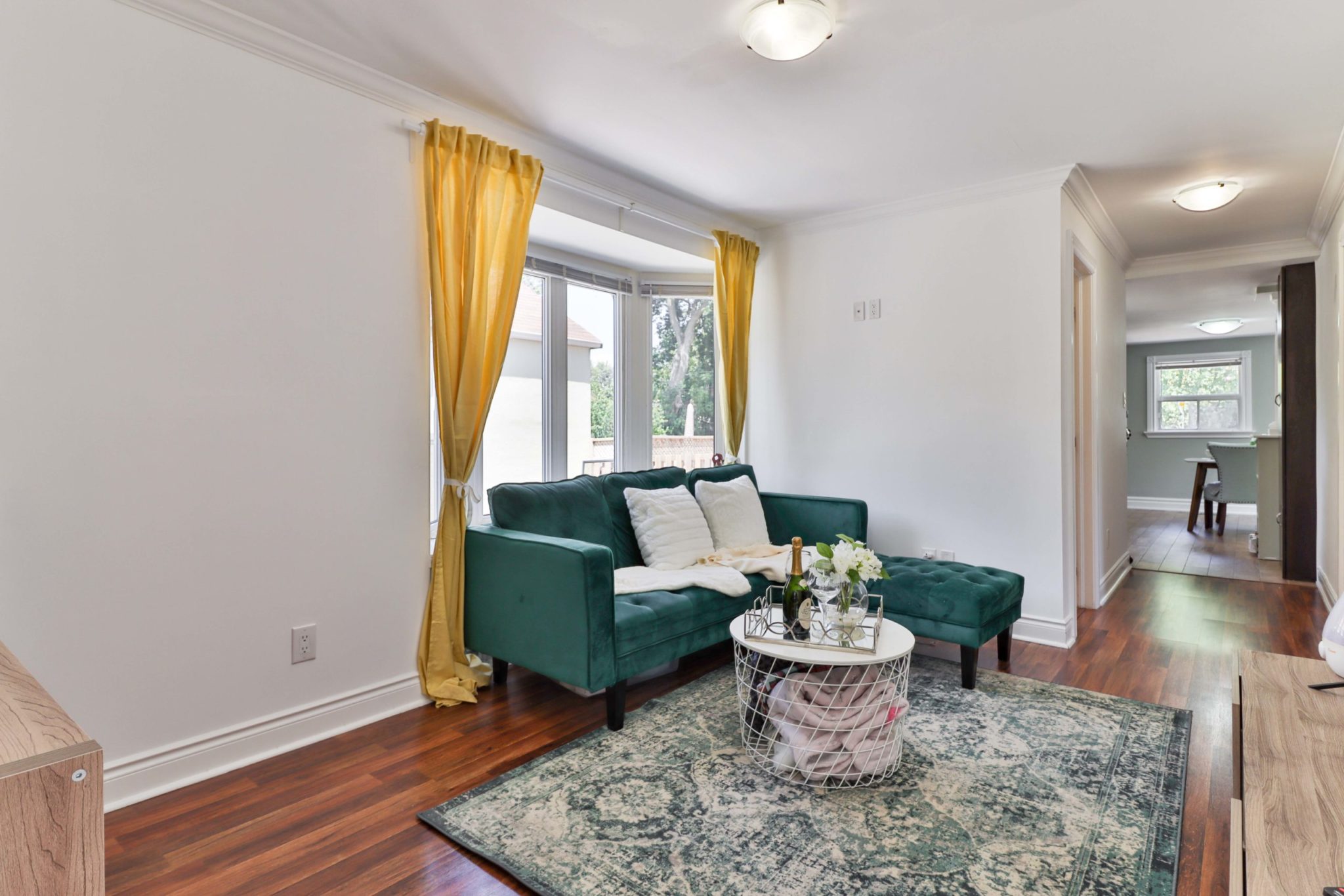 Living room with crown moulding, bay windows and laminate floors.