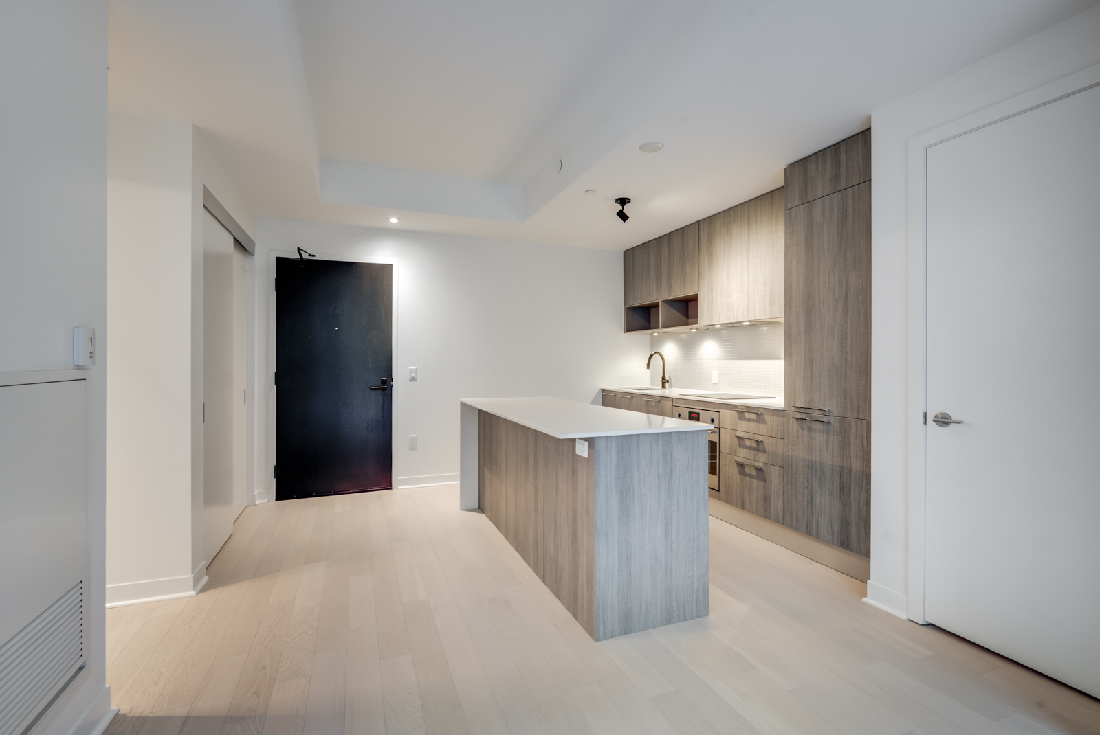 Light-toned laminate floors, kitchen island with wooden base and cabinets with wood finishes.