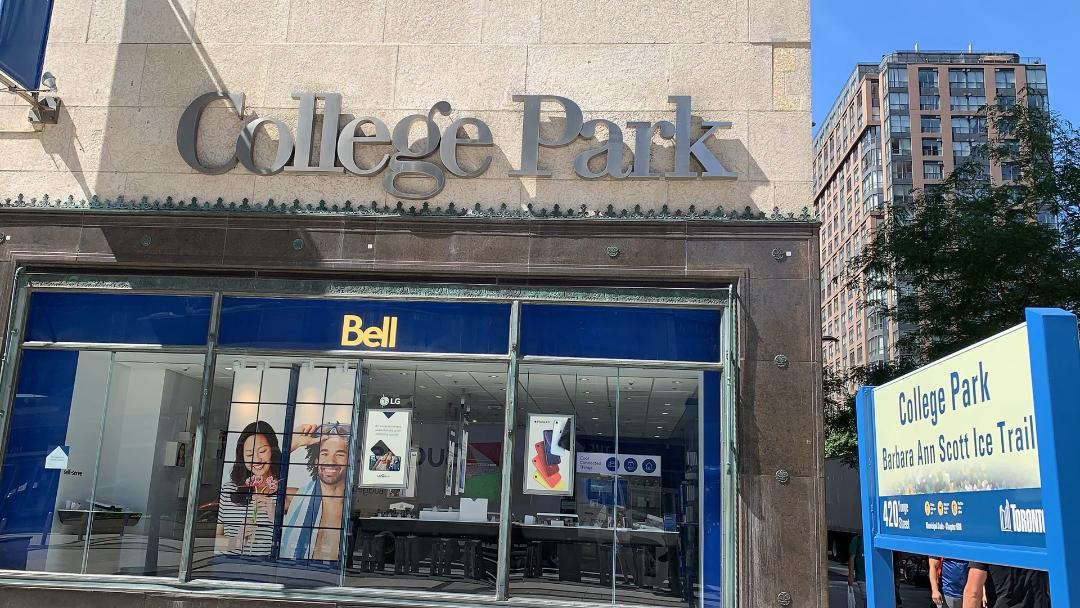 Dark gray sign for College Park mall in Toronto above store.