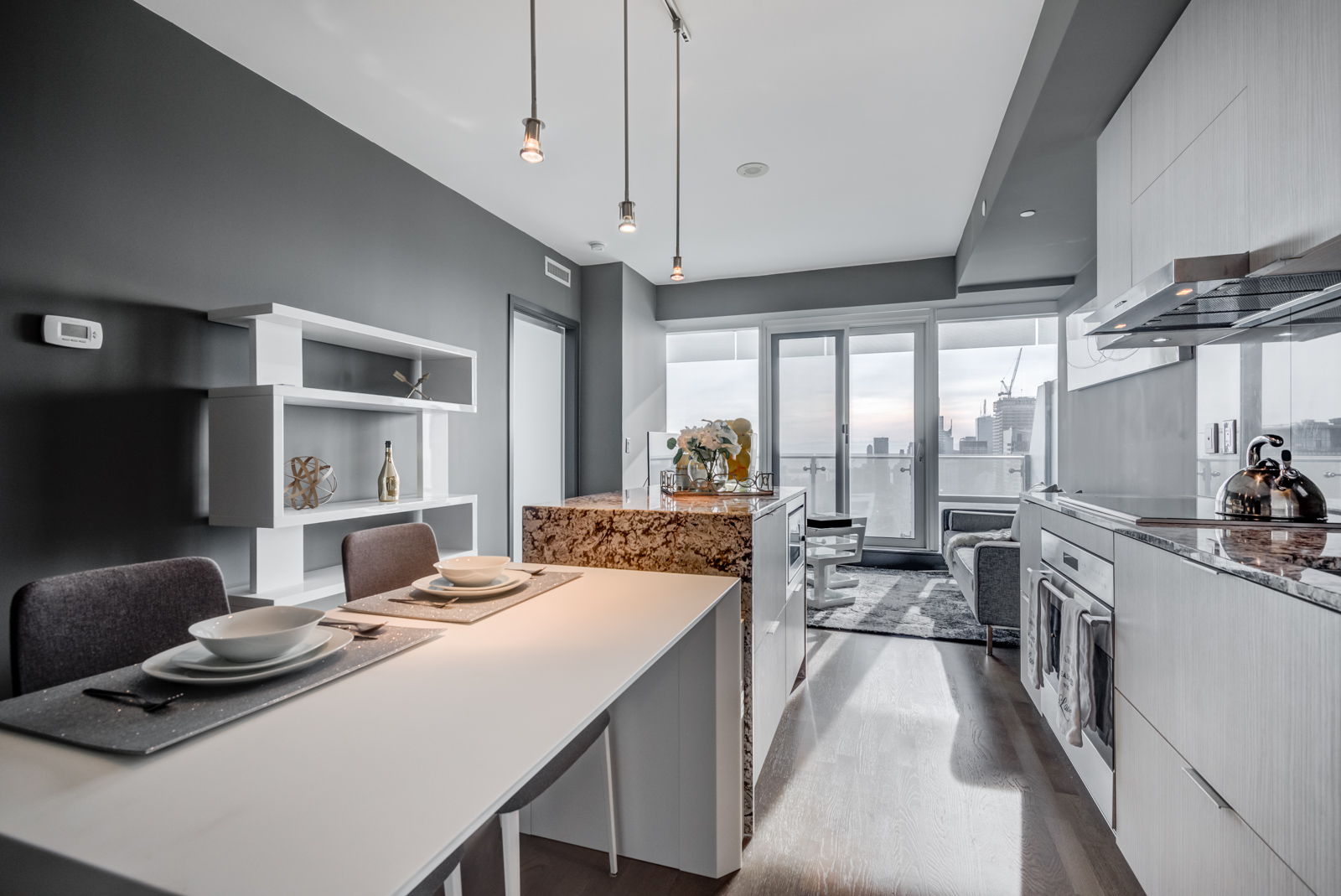 Modern kitchen with white breakfast bar, dark granite counters and stainless-steel appliances covered in sunlight.