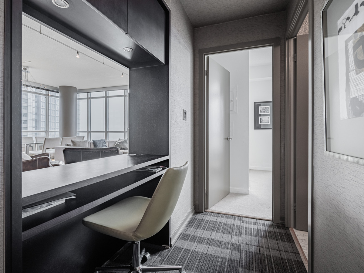 Condo study with recessed lights, overhead cabinets and broadloom carpet.