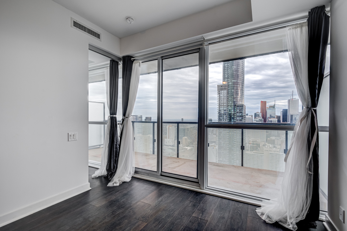 15 Grenville St living room and balcony with large windows offering view of Toronto.