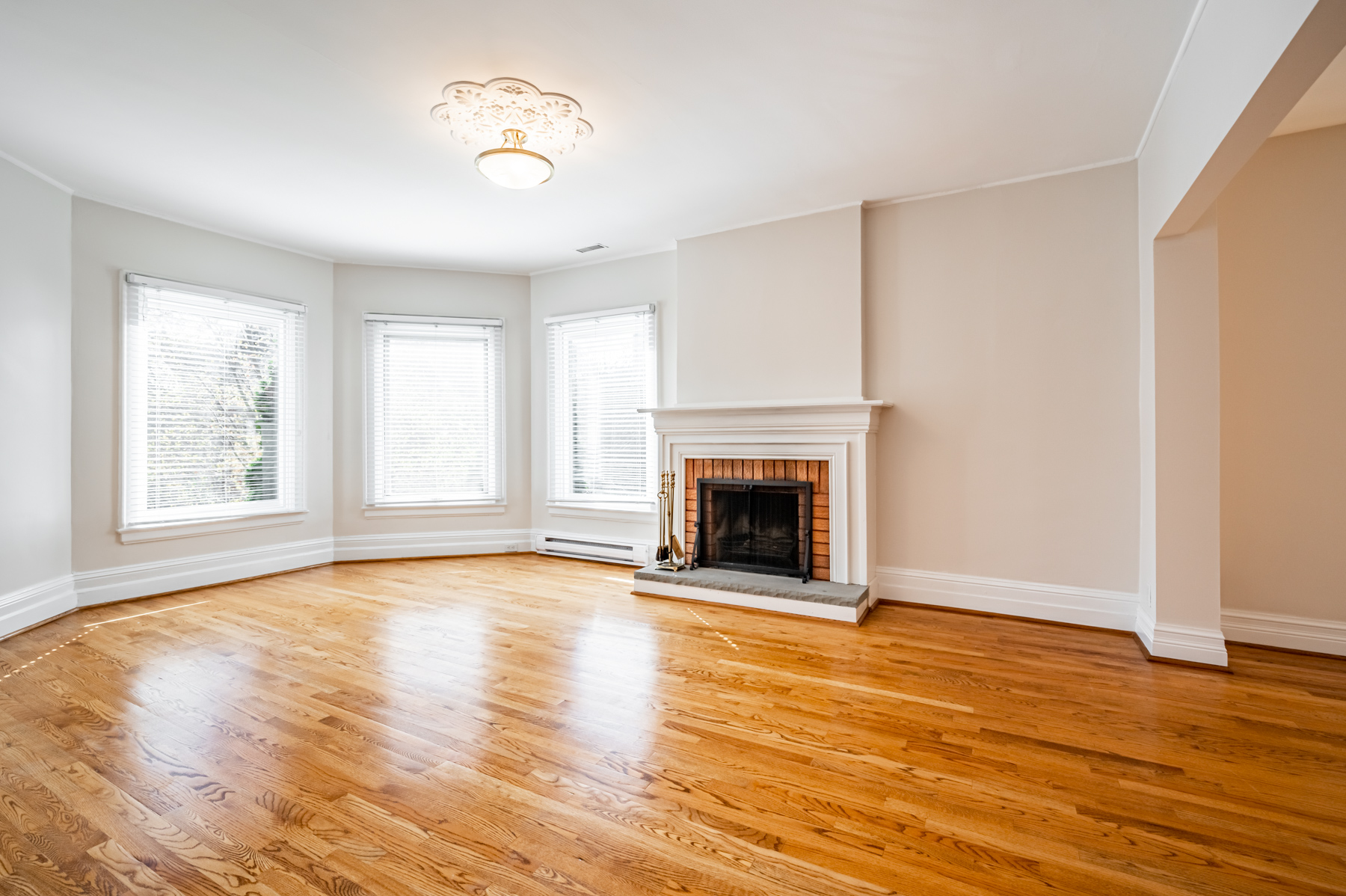 98 Bedford Rd living room with 3 large windows, ceiling lamp and fireplace.