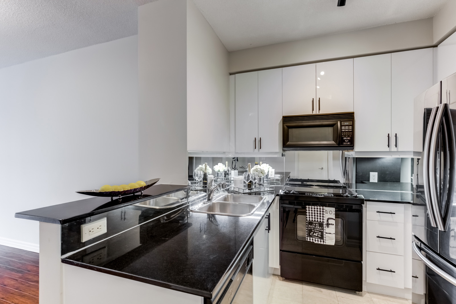 Renovated kitchen with black counters, stove and fridge and white cabinets at 300 Bloor St E Unit 1809.