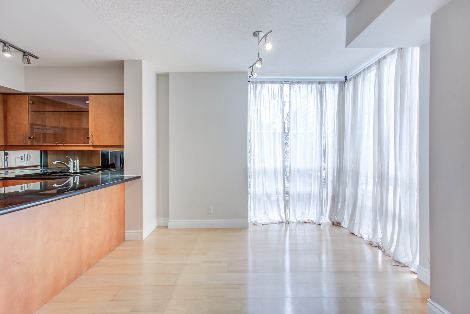 View of 20 Collier St Unit 408 kitchen on left and dining room on right with white curtains.