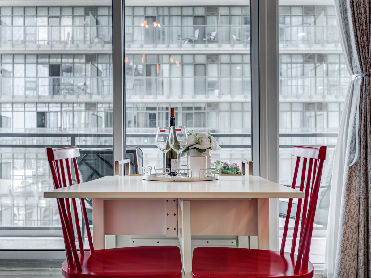 White dining table with wine on tray and 2 red chairs.
