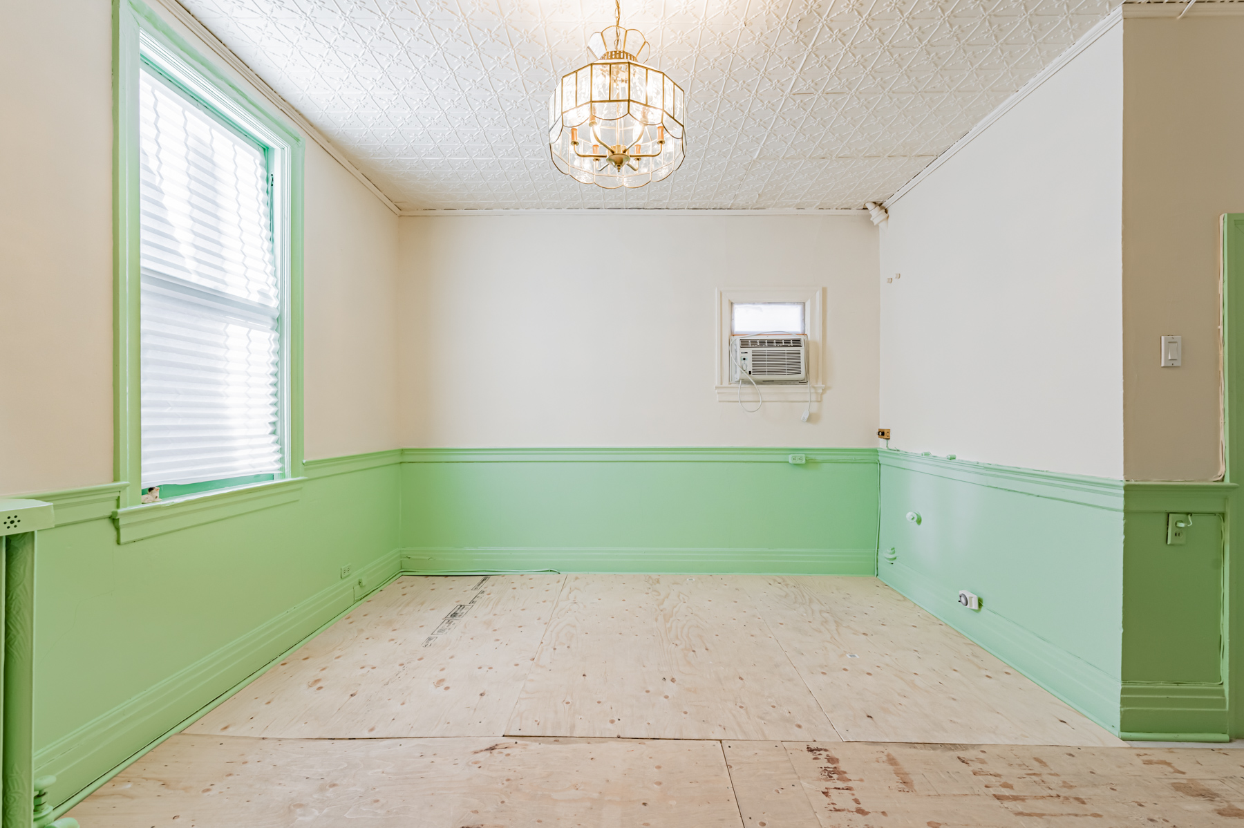 Unfinished kitchen with chandelier and plywood floors.