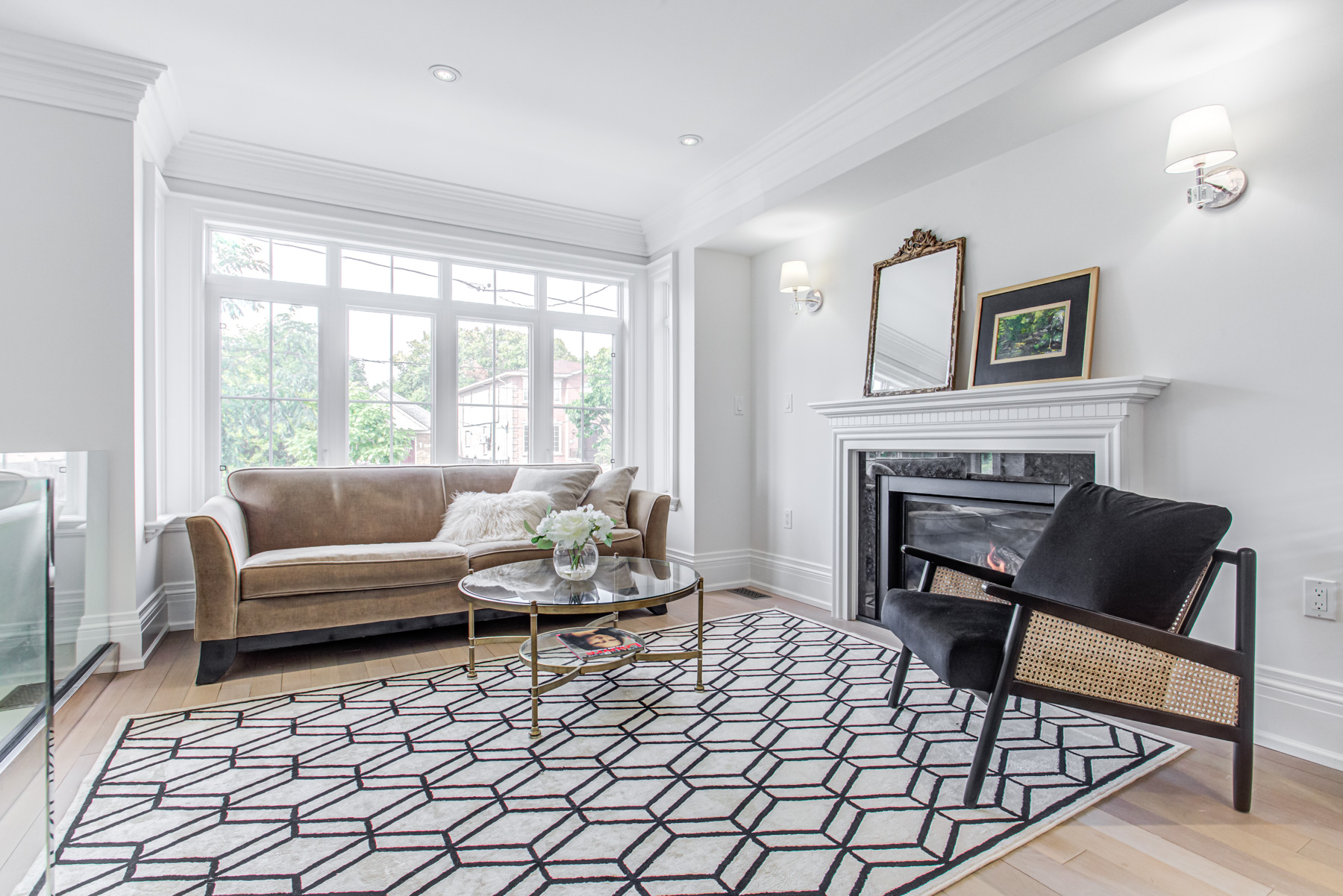 Family room with large windows, wall-mounted lamps and fireplace.