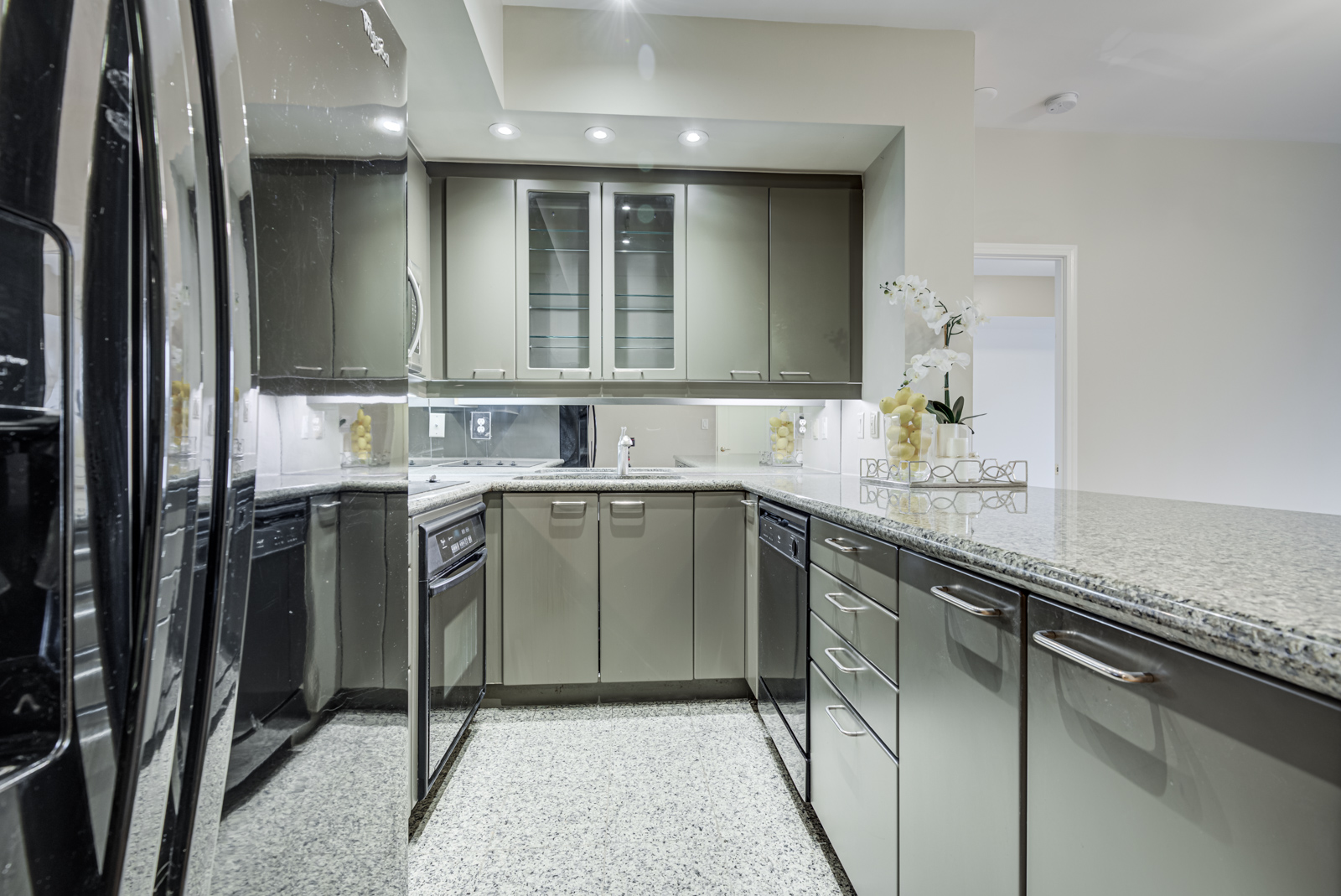 Close up view of black refrigerator, gray cabinets and counters of 77 McMurrich St Unit 308 kitchen.