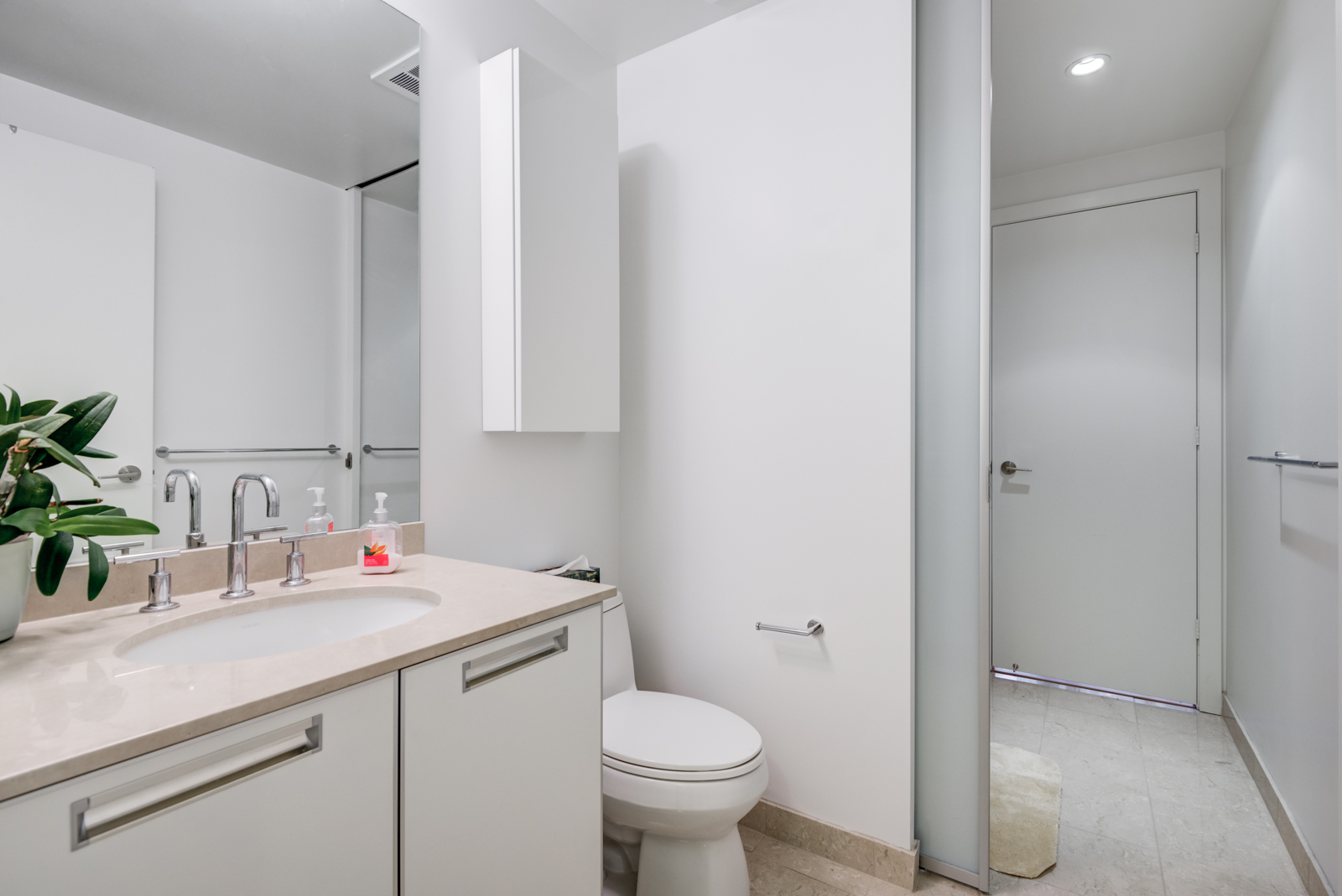 Our first look at 33 Charles St E Unit 911 bathroom. We see the sink, mirror and toilet.