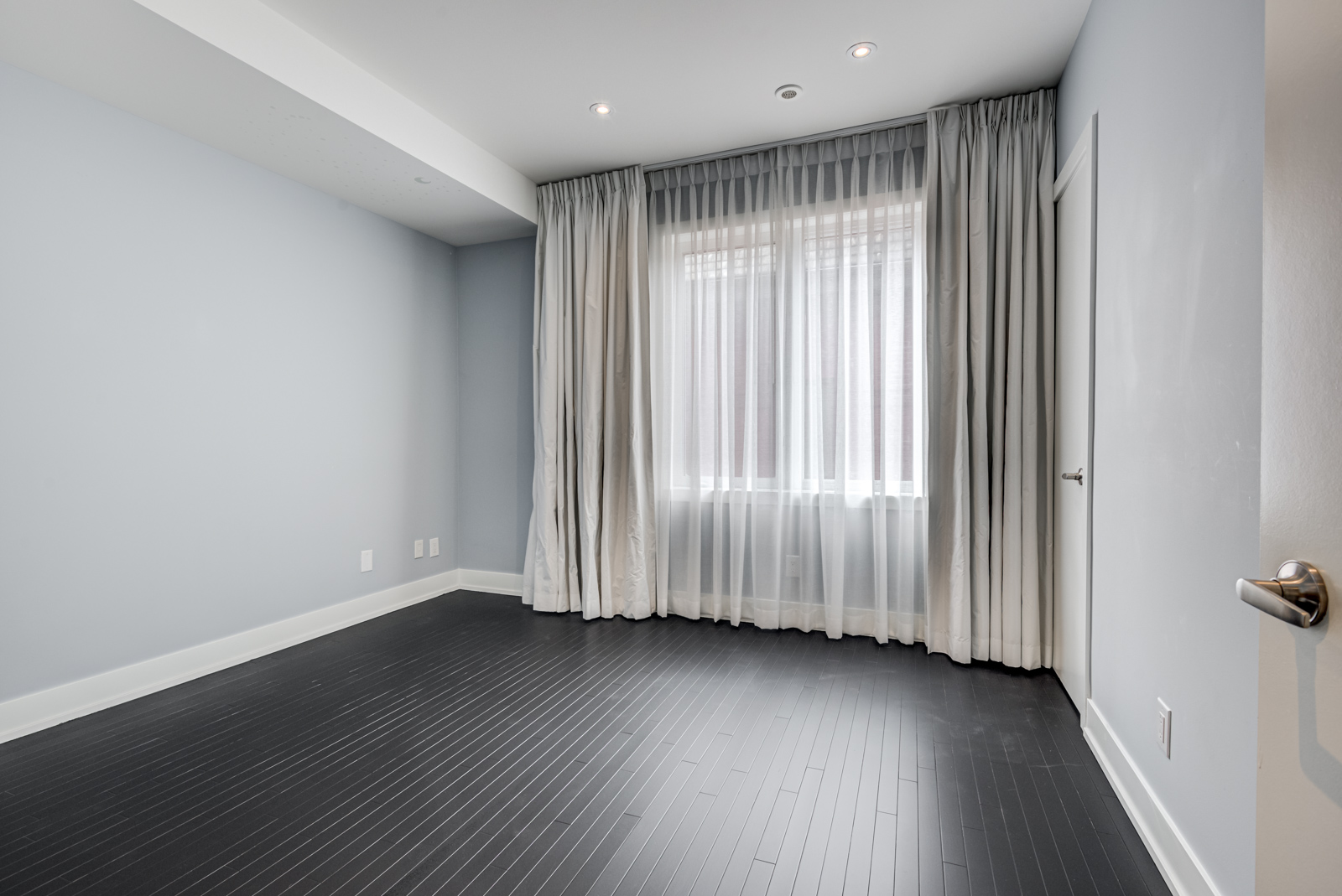 empty bedroom of 12A Cecil with black floors and blue walls