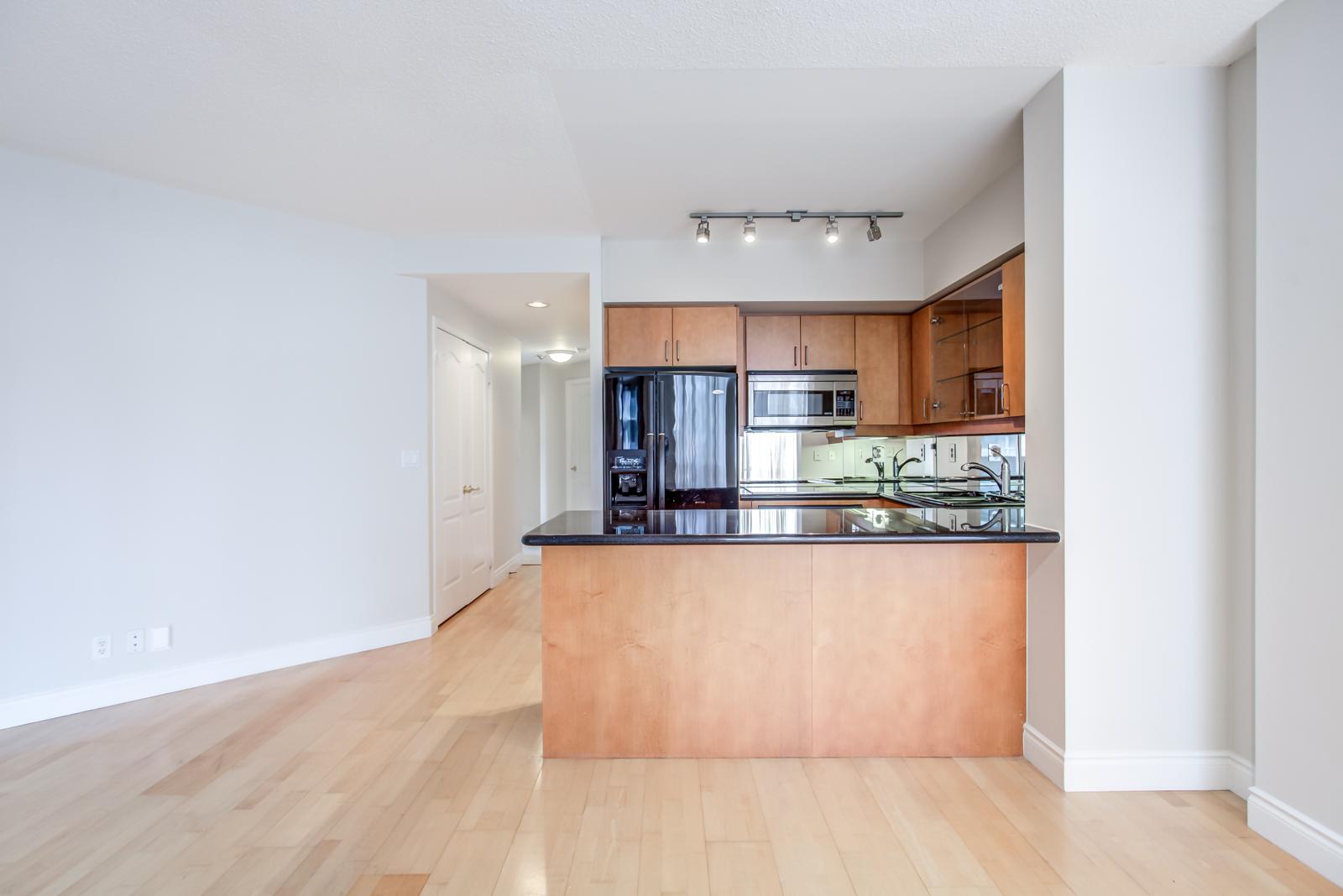 Kitchen with black counter and fridge and brown finishes.