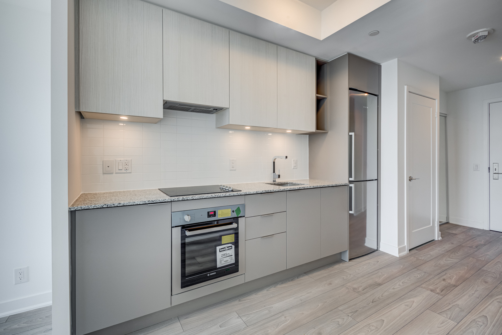 Linear kitchen with built-in appliances and under-cabinet lighting.