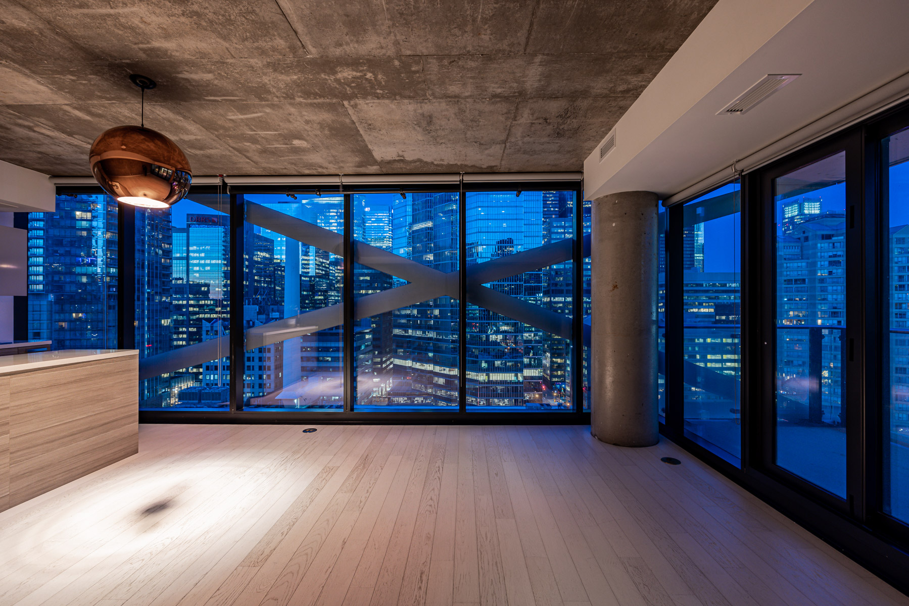 Condo living room windows at night with bluish light.