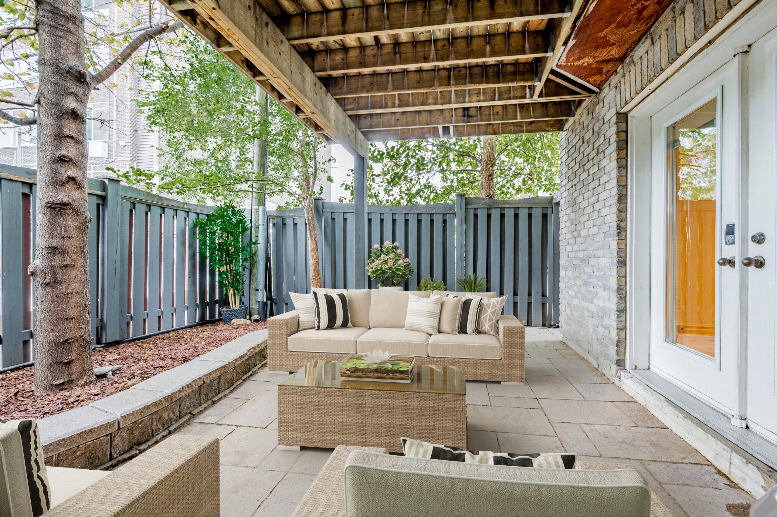 Townhouse backyard with high fence and latticed roof.