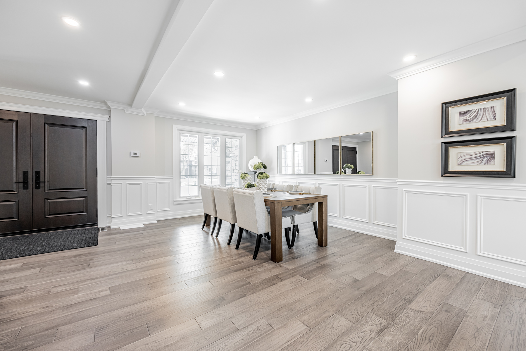 Dining room with dark double doors, gray walls, hardwood floors and wainscoting.