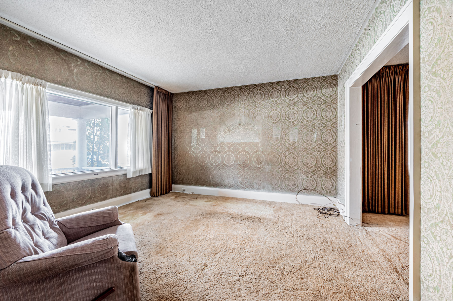 House living room with broadloom carpet, wallpaper and large window.