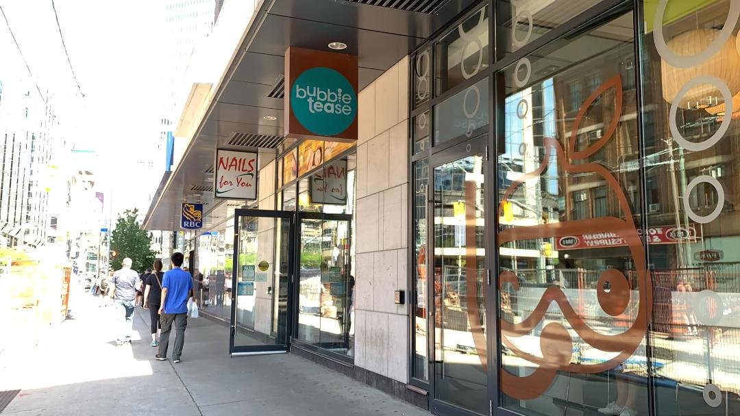 Sidewalk in Dundas, Toronto with pedestrians and stores, including Bubble Tease.